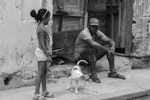 mężczyźni obok małej kubańskiej dziewczyny, trzymając biały pies, - horizontal black and white toned image two people zdjęcia i obrazy z banku zdjęć