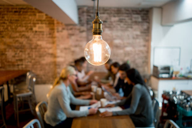 Creative office Group of business people brainstorming at a creative office and a light bulb in the foreground light bulb photos stock pictures, royalty-free photos & images