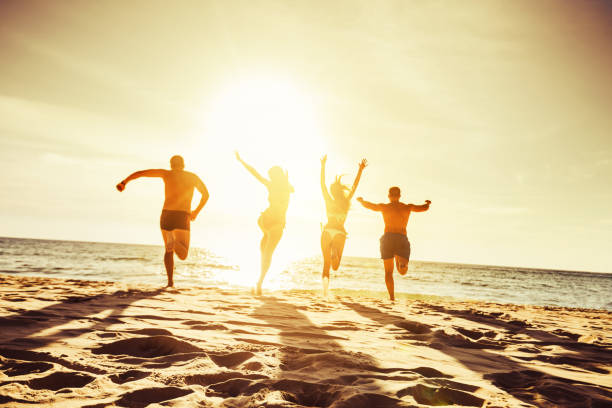 Beach concept group four friends Silhouettes of four friends runs at sunset beach to the sea sunset beach hawaii stock pictures, royalty-free photos & images