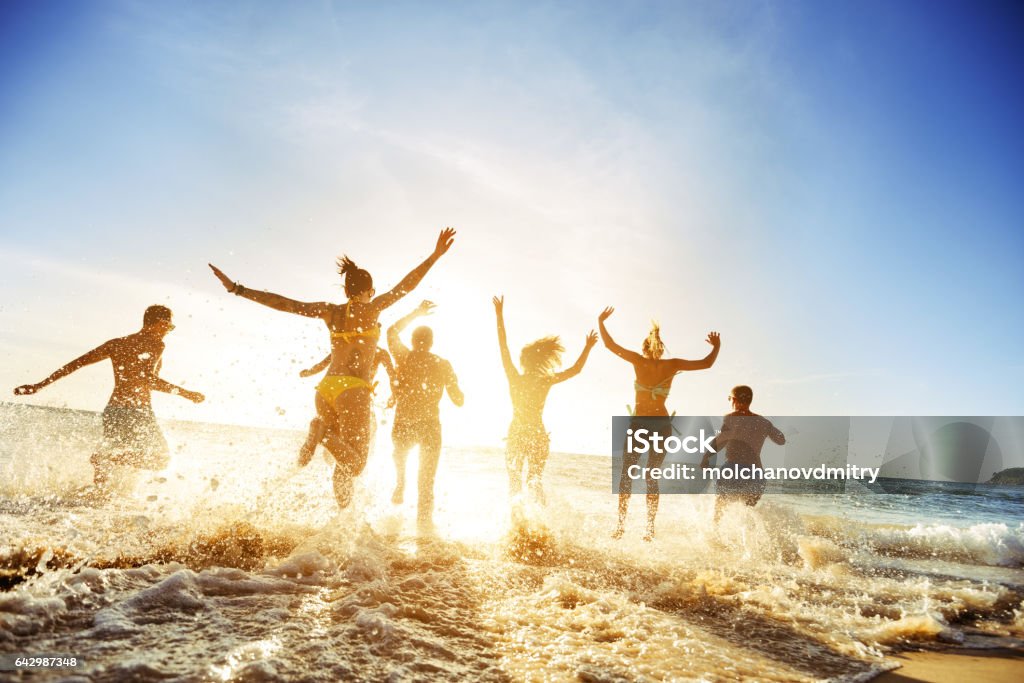 Crowd people friends sunset beach holidays Crowd of people or friends runs to sunset sea. Beach holidays travel concept Beach Stock Photo