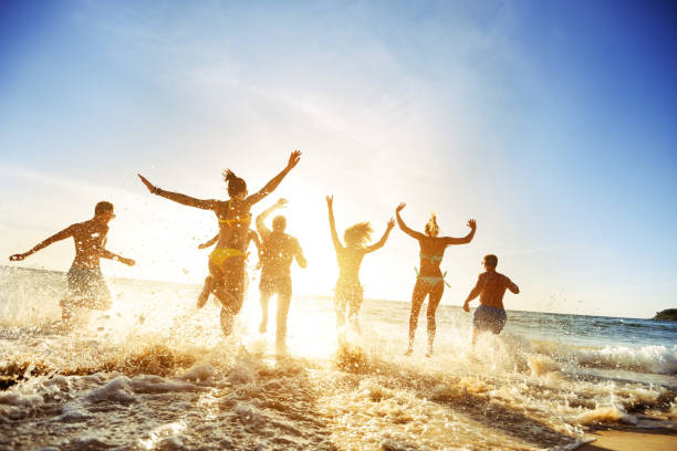 Crowd people friends sunset beach holidays Crowd of people or friends runs to sunset sea. Beach holidays travel concept summer fun stock pictures, royalty-free photos & images