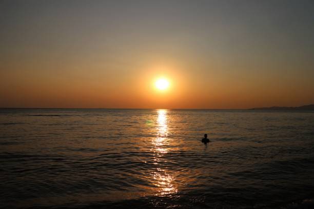 istock Sunset Over Sea with Swimmer 642994774