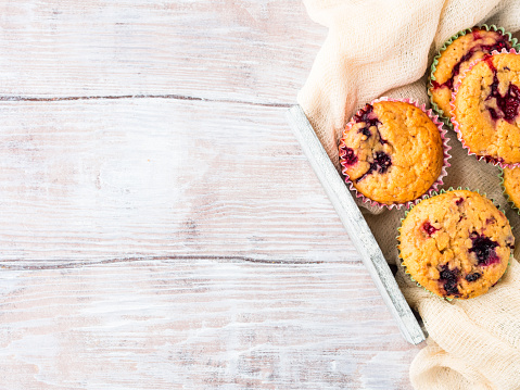 Berry muffins in wooden tray napkin textile. Spring summer holiday breakfast set with tea. Top view