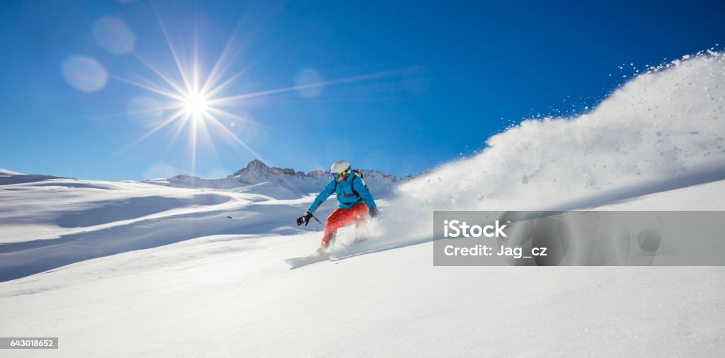 Freerider snowboarder running downhill Freerider snowboarder running downhill in beautiful Alpine landscape. Fresh powder snow, blue sky on background. Snowboarding Stock Photo