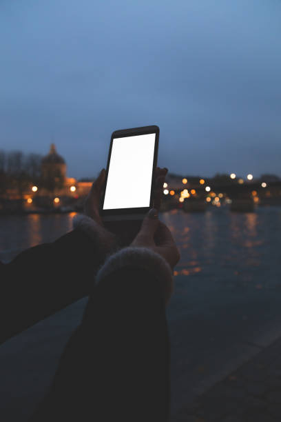 istock Using cellphone at night on a sidewalk near Seine river. 643021276