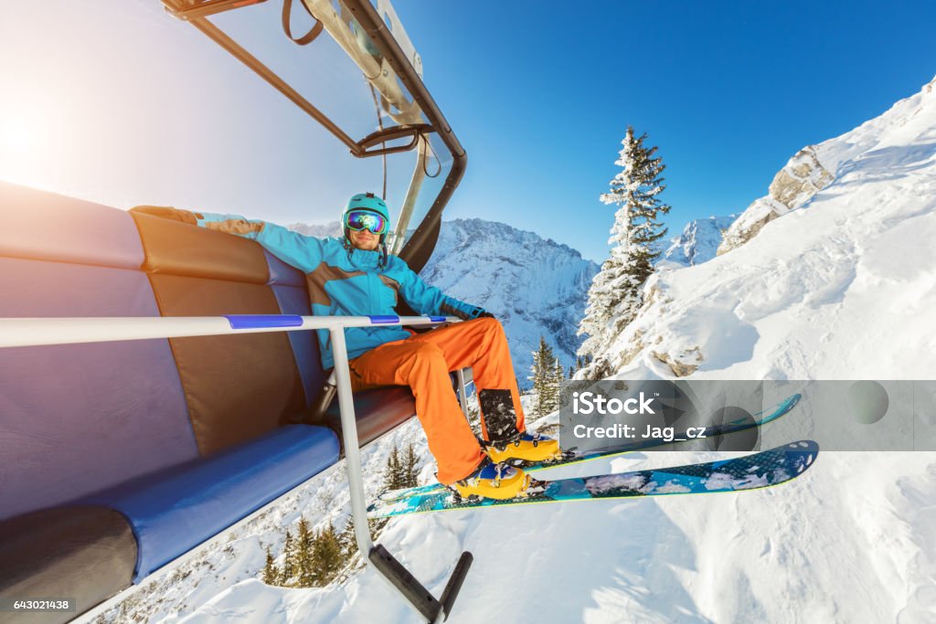 Skier sitting at ski chair lift in Alpine mountains Skier sitting at ski chair lift in beautiful sunny day, Alpine mountains. Concept of skiing Ski Lift Stock Photo