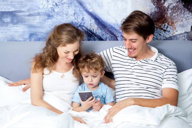 istock Happy parents and little son looking at smartphone 643025358