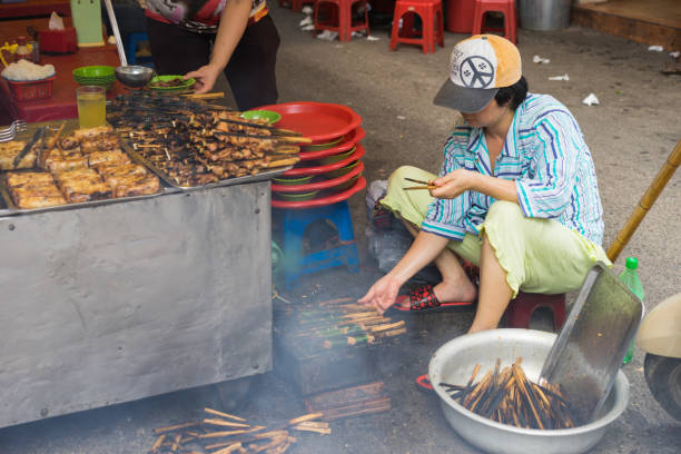 ハノイ、ベトナム - 4月5、2015:女性の焼きバーベキュー肉 - 「バンチャ」の成分は、バーベキュー肉、春巻き、春季と新鮮な野菜と有名なベトナムのヌードルスープです - barbecue grill broiling barbecue vegetable ストックフォトと画像