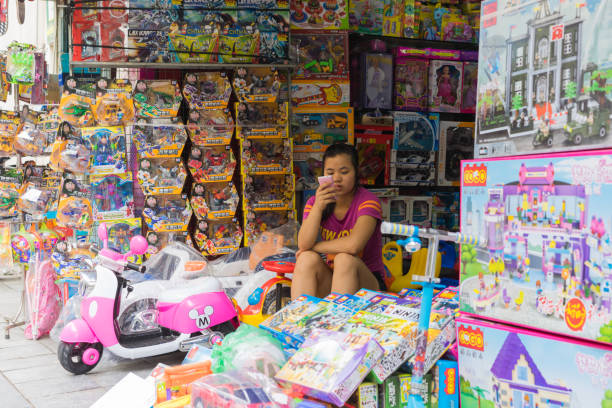 Hanoi, Vietnam - Apr 5, 2015: Children toy shop in Hang Can street. Focus on the sale woman Hanoi, Vietnam - Apr 5, 2015: Children toy shop in Hang Can street. Focus on the sale woman vietnamese girls for sale stock pictures, royalty-free photos & images