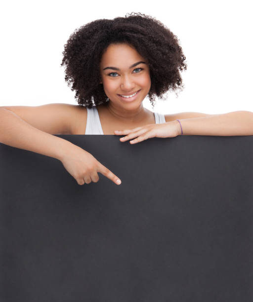 Young Smileing teenager african girl hold black blank paper and shows on it. stock photo