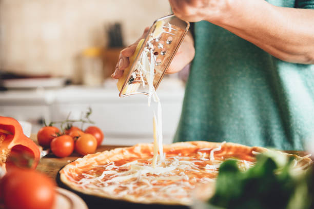 woman preparing pizza - recipe ingredient grater cheese grater imagens e fotografias de stock