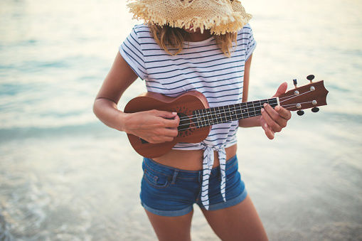 Young woman with straw hat playing ukulele