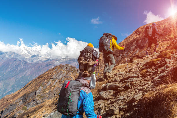 istock Group of People walking up on Mountain Trail with Sun 643057600