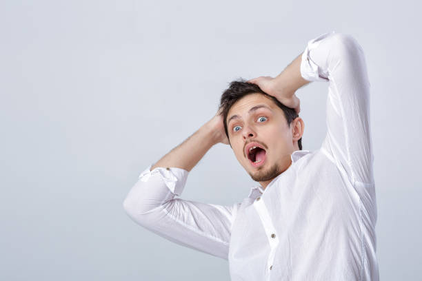 istock young attractive surprised brunette man in white shirt on gray b 643060488