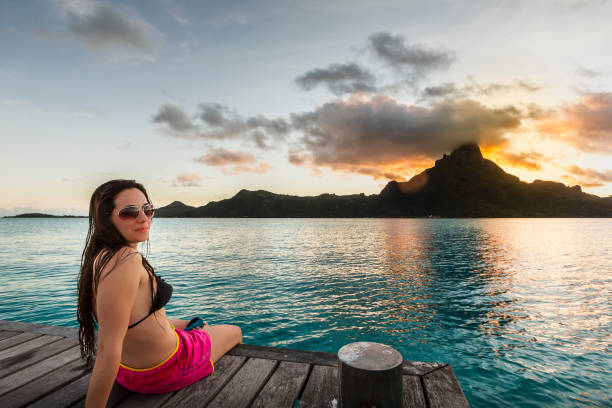 istock Beautiful woman watching sunset on idyllic pier in Bora Bora 643067252