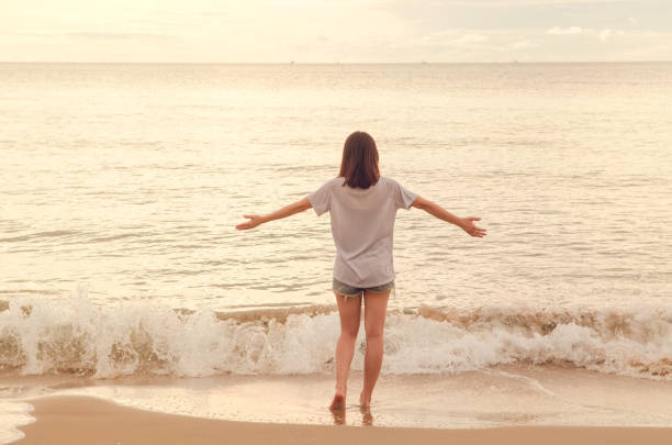 Freedom and happiness woman on beach. She is enjoying serene sea nature during travel holidays vacation outdoors sunset.