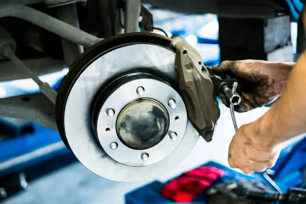 Scene of mechanic assembling Car DiscBrake. selective focused.