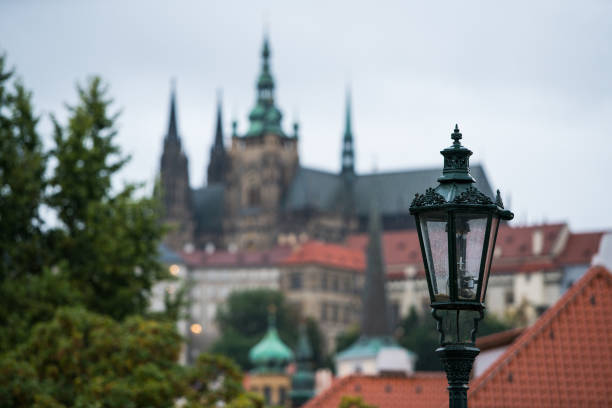 Prague, Czech Republic - October 11, 2024: Close-up of an ornate black iron street lamp in Nove Mesto, surrounded by historic buildings with European architectural details.