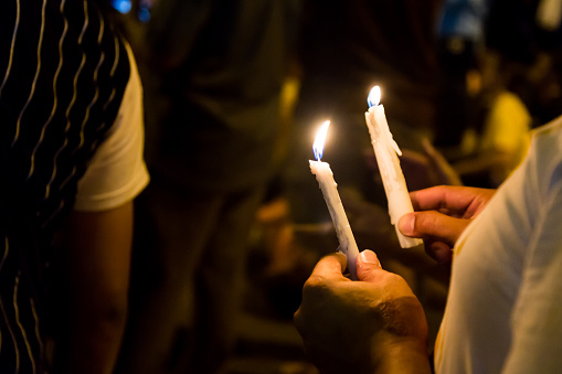 Group of people holding candle vigil in darkness seeking hope, worship, prayer