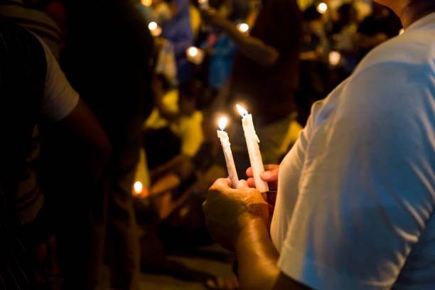 istock People holding candle vigil in darkness 643083034