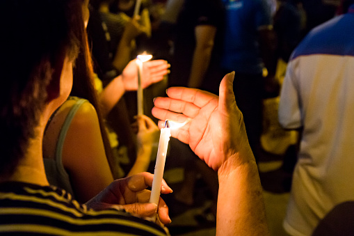 Group of people holding candle vigil in darkness seeking hope, worship, prayer