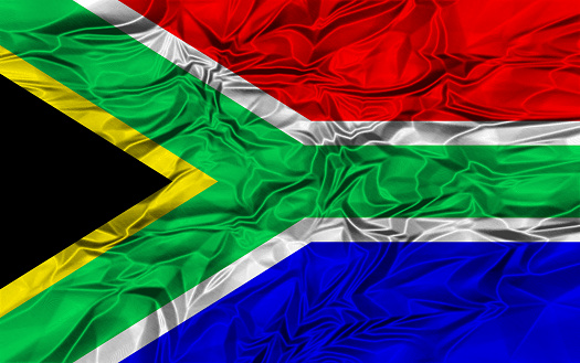 South Africa country flag on wavy silk textile fabric background.