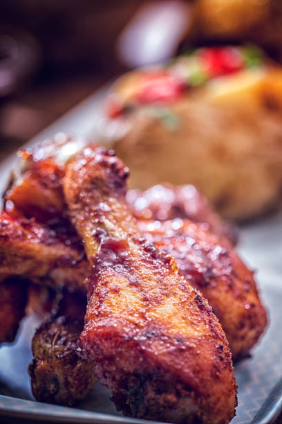 istock Eating Spicy Chicken Wings with Baked Potato and Corn 643086682