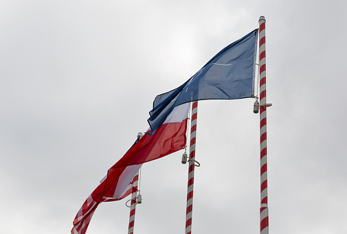 Flags of Nato, Poland and USA waving outdoor closeup against cloudy sky.