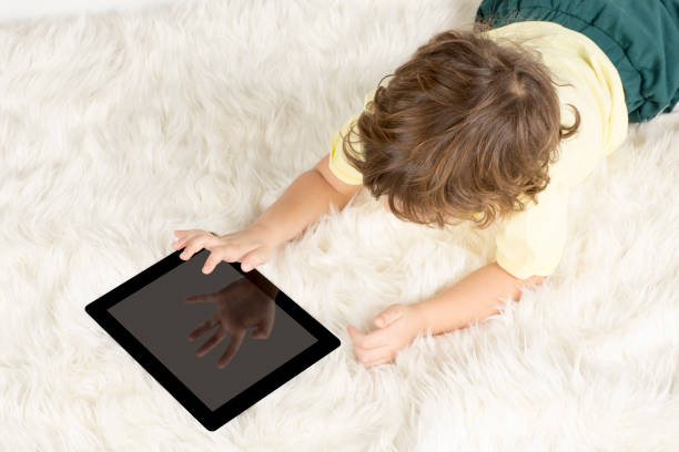 ragazzino che lavora tablet su tappeto - looking at camera full length outdoors image technique foto e immagini stock