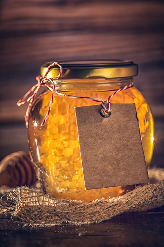 Honey in jar with honeycomb on wooden background