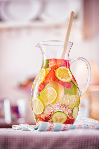 Infused water with fresh strawberries, lime, lemon and basil served in a glass.