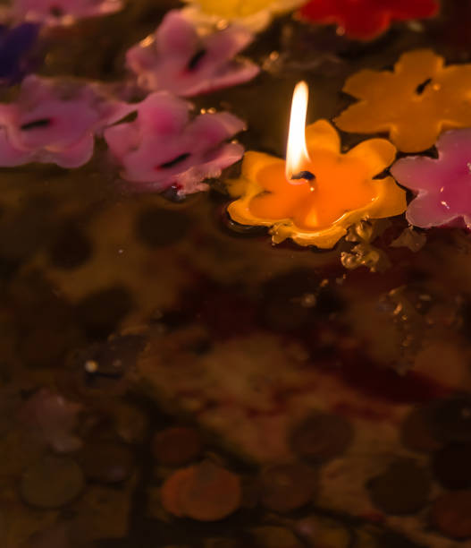 istock flower candle flame light floating in holy pond with coins underneath 643094888