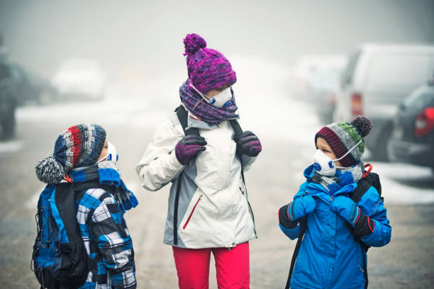 Kids going to school in the smog Three kids wearing pollution masks and backpacks are walking to school in the smog. The air is thick with mist and smog.

 smog car stock pictures, royalty-free photos & images