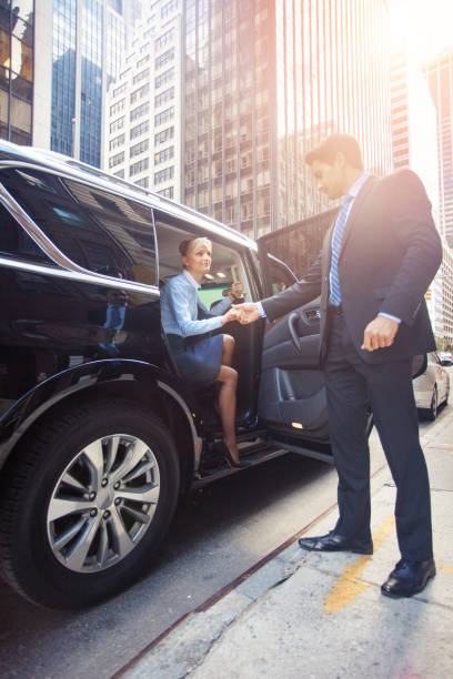 Business woman getting out of car with man helping her out stock photo