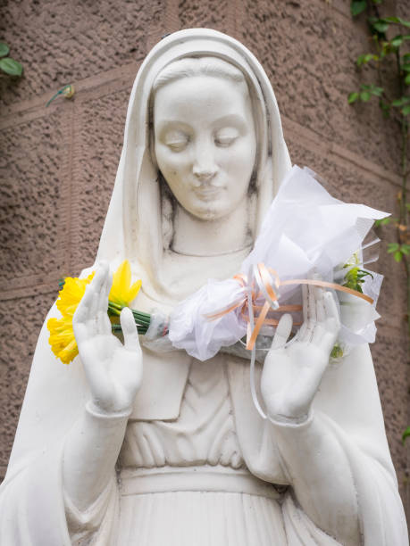 istock Virgin Mary Statue with Flower Offerings 643116082
