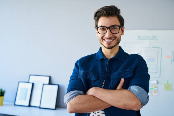 istock Happy website designer, standing in office wearing glasses 643134056