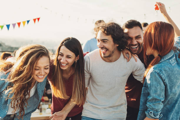 Ecstatic group enjoying the party Multi-ethnic group of young people on a rooftop party friends laughing stock pictures, royalty-free photos & images