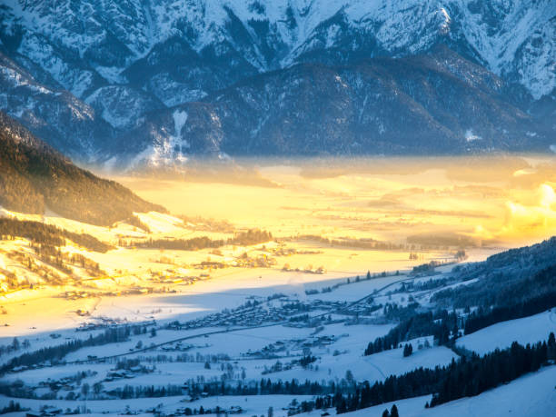 rano w alpejskiej dolinie. zimowa mgła oświetlona promieniami wschodzącego słońca, leogang, austria - ski resort village austria winter zdjęcia i obrazy z banku zdjęć