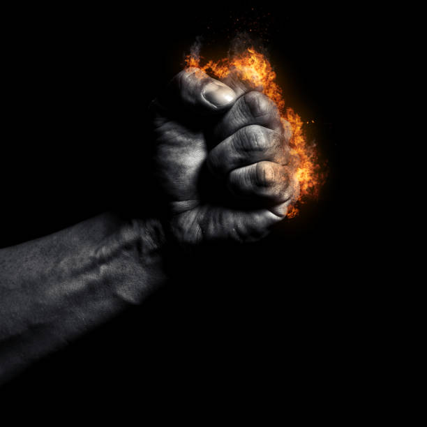 Burning man's clenched fist on a black background stock photo