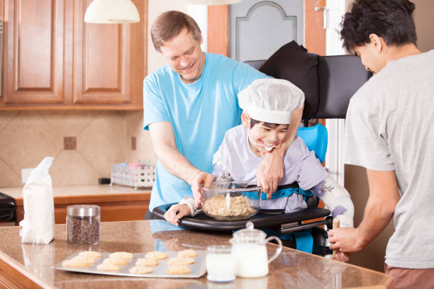 Disabled boy in stander baking cookies with father and brother