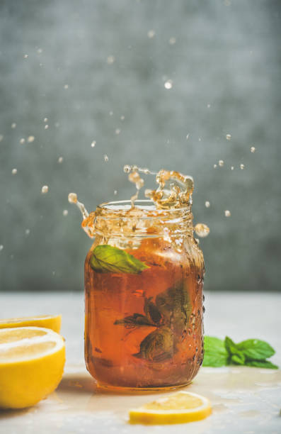 Iced tea with bergamot, lemon, mint in jar with splashes