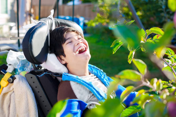 휠체어를 탄 장애인 소년이 뒷마당에서 웃고 있다. 스톡 사진