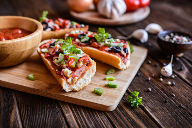 pizza baguette avec bacon, salami, fromage et légumes - french bread pizza photos et images de collection