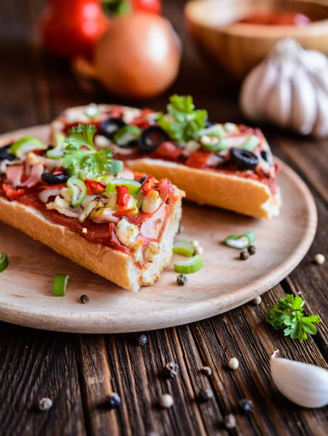 pizza baguette avec bacon, salami, fromage et légumes - french bread pizza photos et images de collection