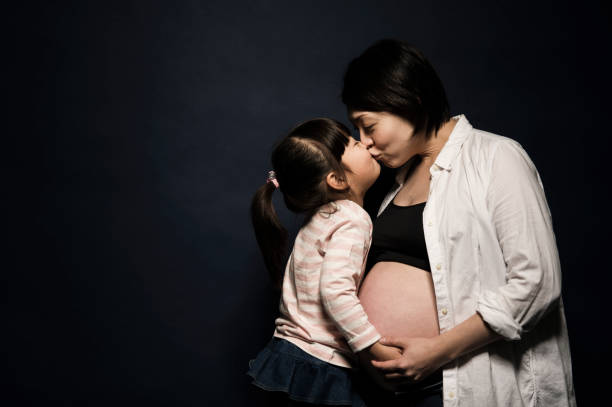 Asian child kiss her pregnant mother's belly