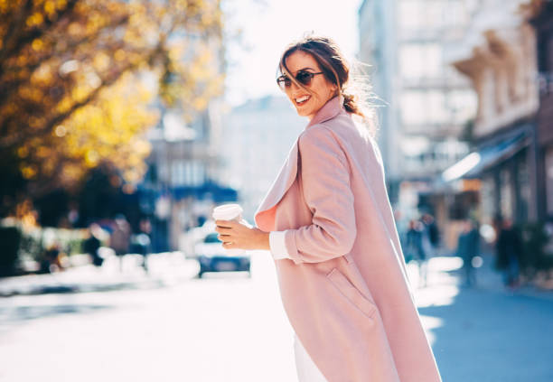 Beautiful elegant woman A young woman drinking coffee on her way to work. coat stock pictures, royalty-free photos & images