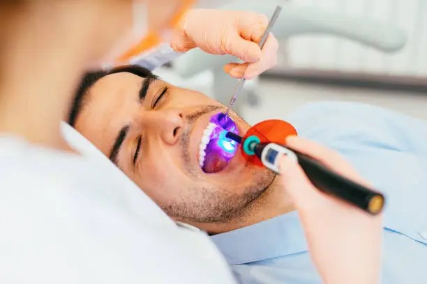 Female dentist using a dental curing light.