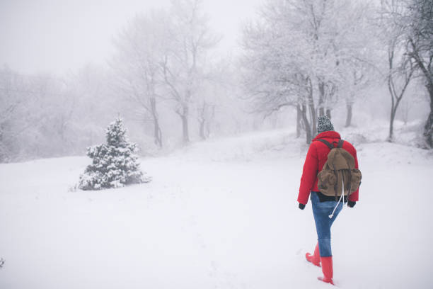 Woman with a backpack walking through winter forest.