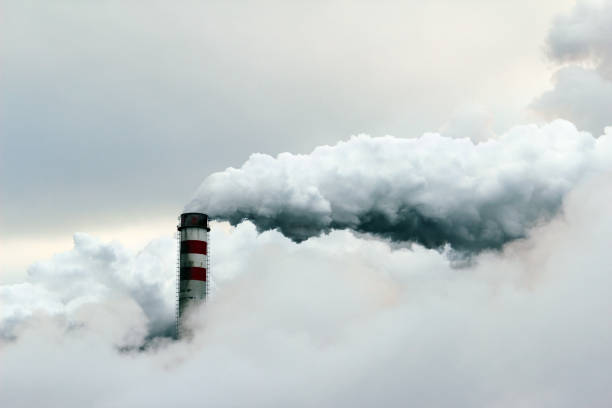 big cloud of smoke coming out of  power plant chimney stock photo
