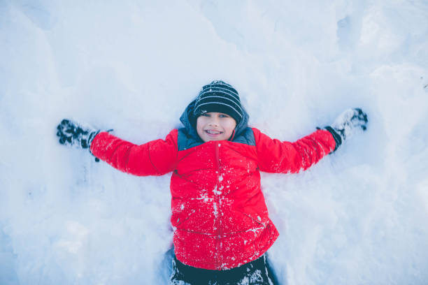 istock Young boy with braces in red coat playing in snow 643283072